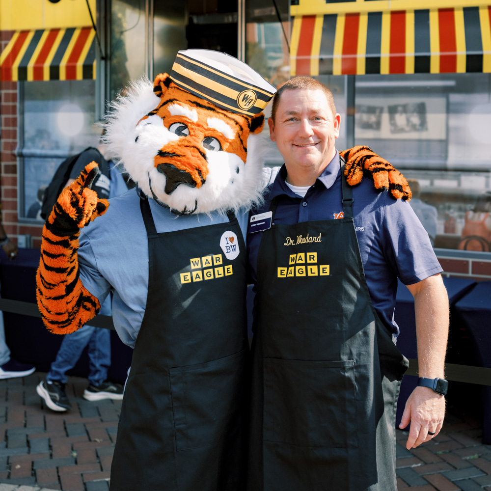 Bobby Woodard and Aubie wearing cooking aprons in front of a Waffle House truck