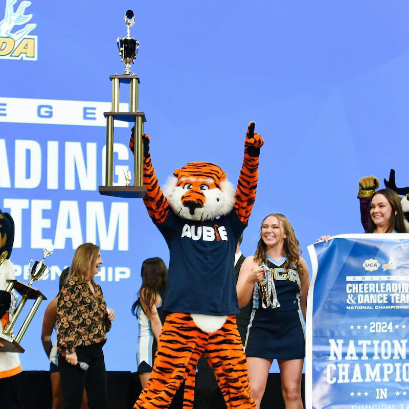 Aubie hoisting the UCA National Championship trophy on stage