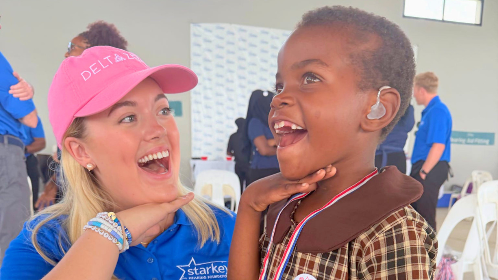 Girl and child posing for camera showing off a hearing aid.