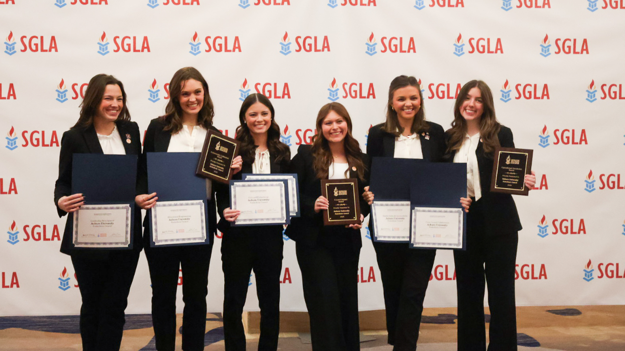 Panhellenic Council in front of an SGLA backdrop holding recognition plaques and certificates