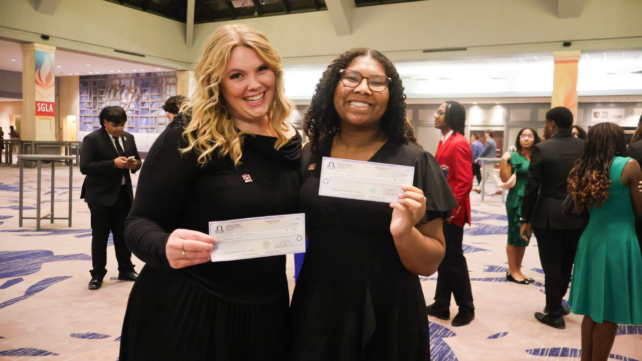 Montana Maslonka (left) and Camaya Doxie (right) smile while holding award checks