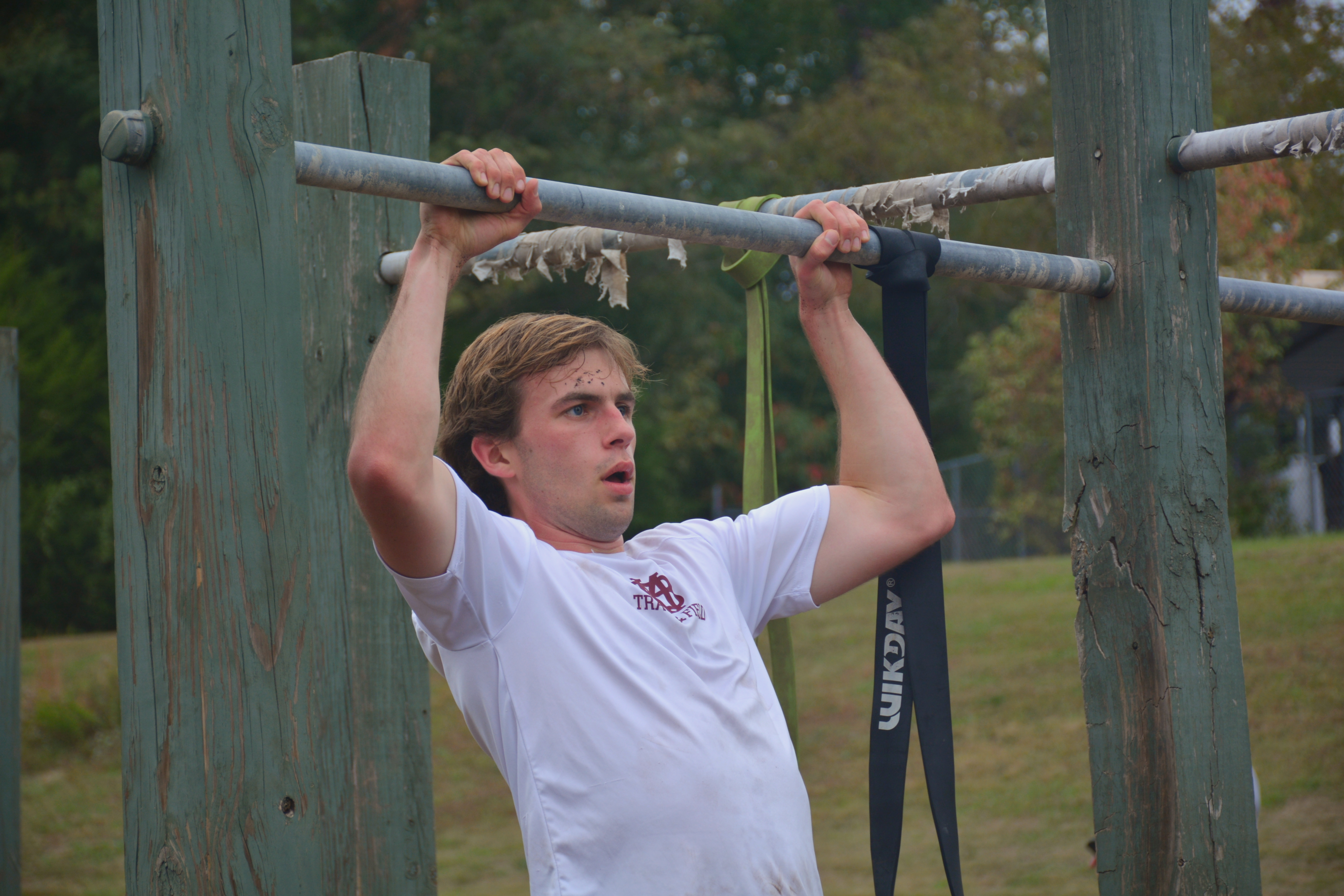 Man performing a pull up on an outdoor bar.