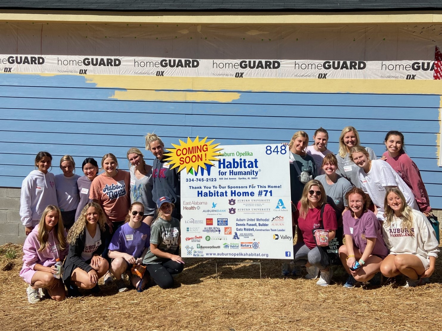 Women posing in front of a Habitat for Humanity sign.