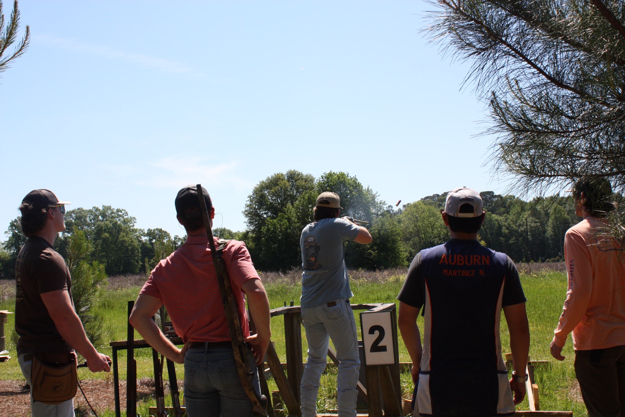 Five men facing away from the camera towards an open field.