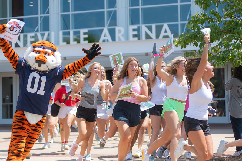 Aubie running with students in front of Neville Arena