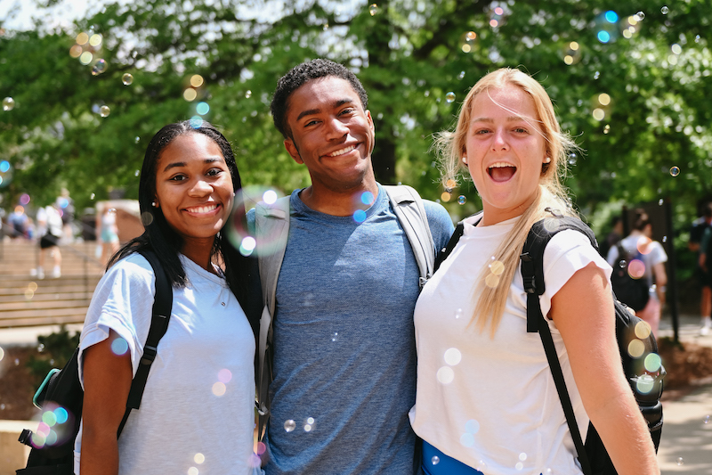 three students posing for a photo outside