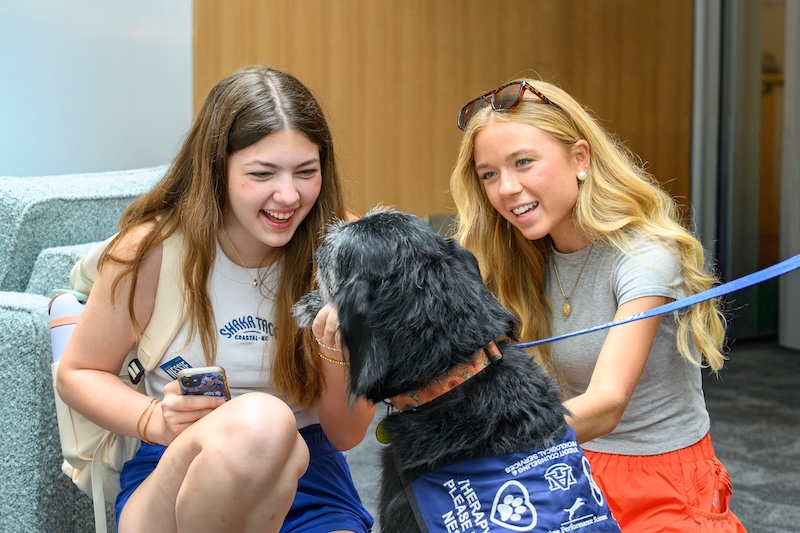 two students petting a one of the SCPS therapy dogs