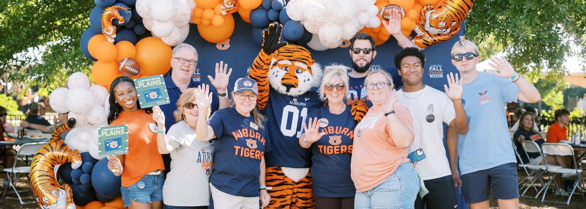 parents and students pose in front of a backdrop at the 2026 fall family tailgate