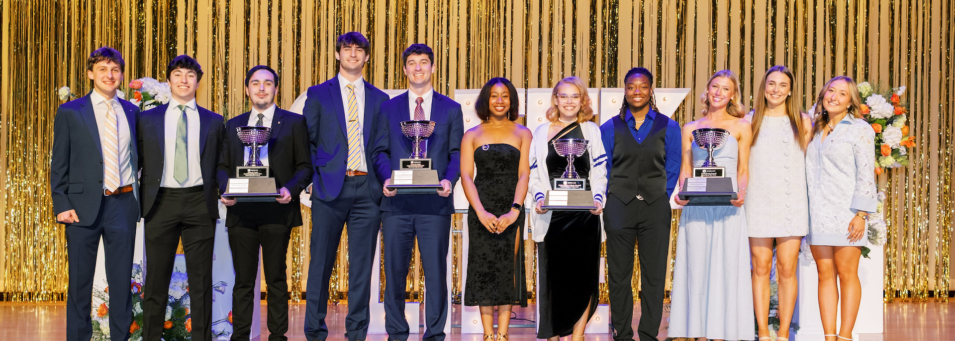 award recipients at the Greek Life Awards ceremony stand on stage holding trophies