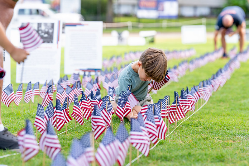 young boy placing small US flags in the ground