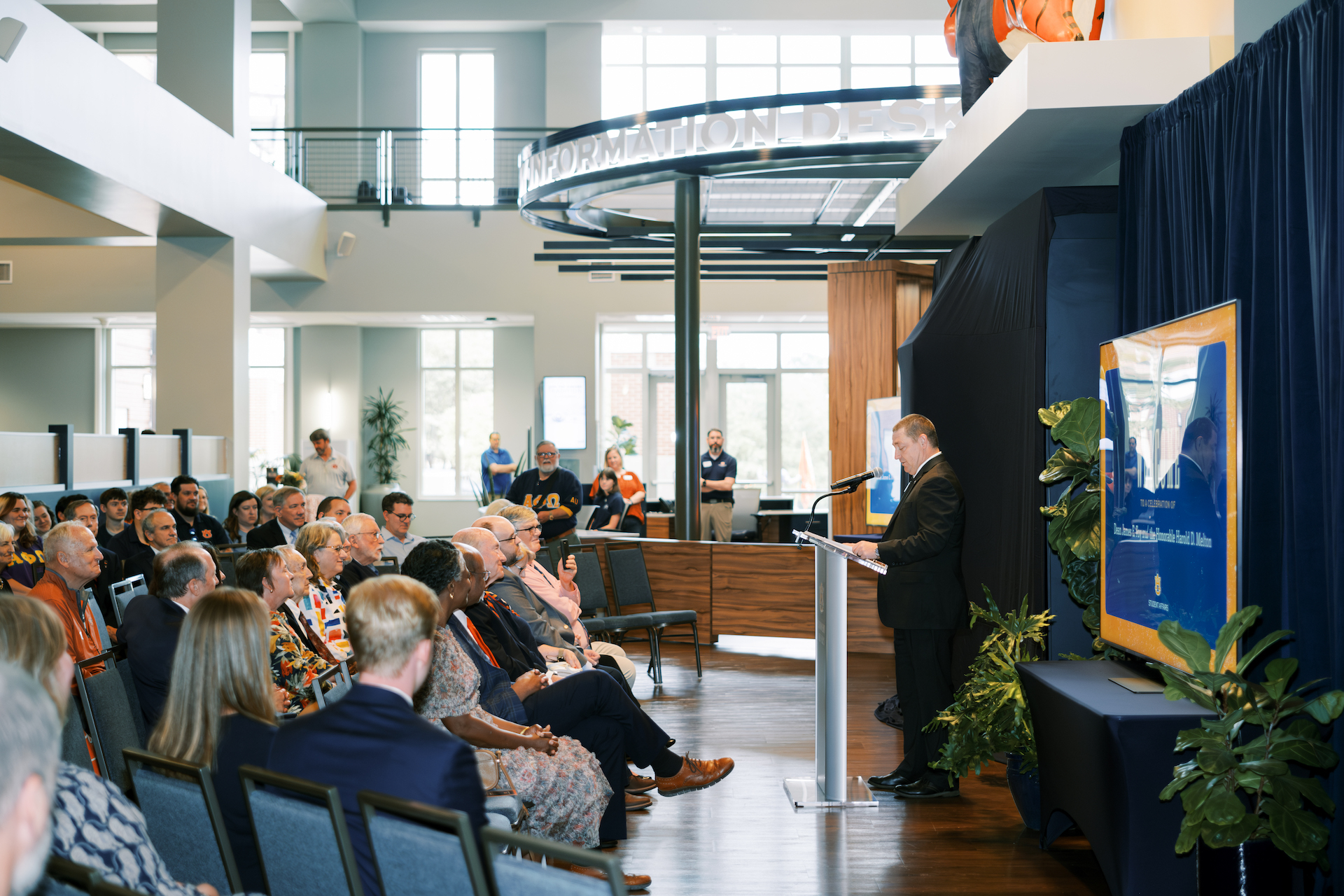 Dr. Woodard speaks to a seated crowd beside the Foy Information Desk
