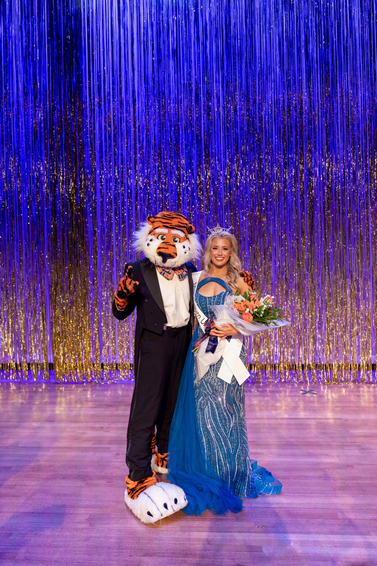 Girl with crown smiling with the Auburn Mascot, Aubie
