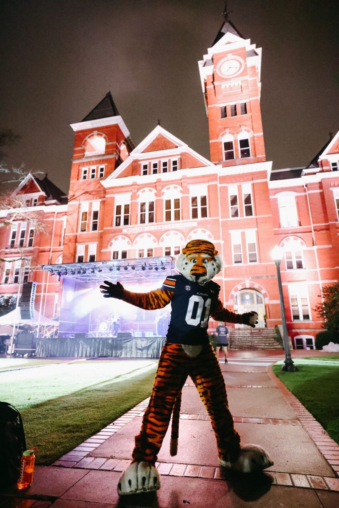 Aubie posing with Samford Hall and a stage in the backroung