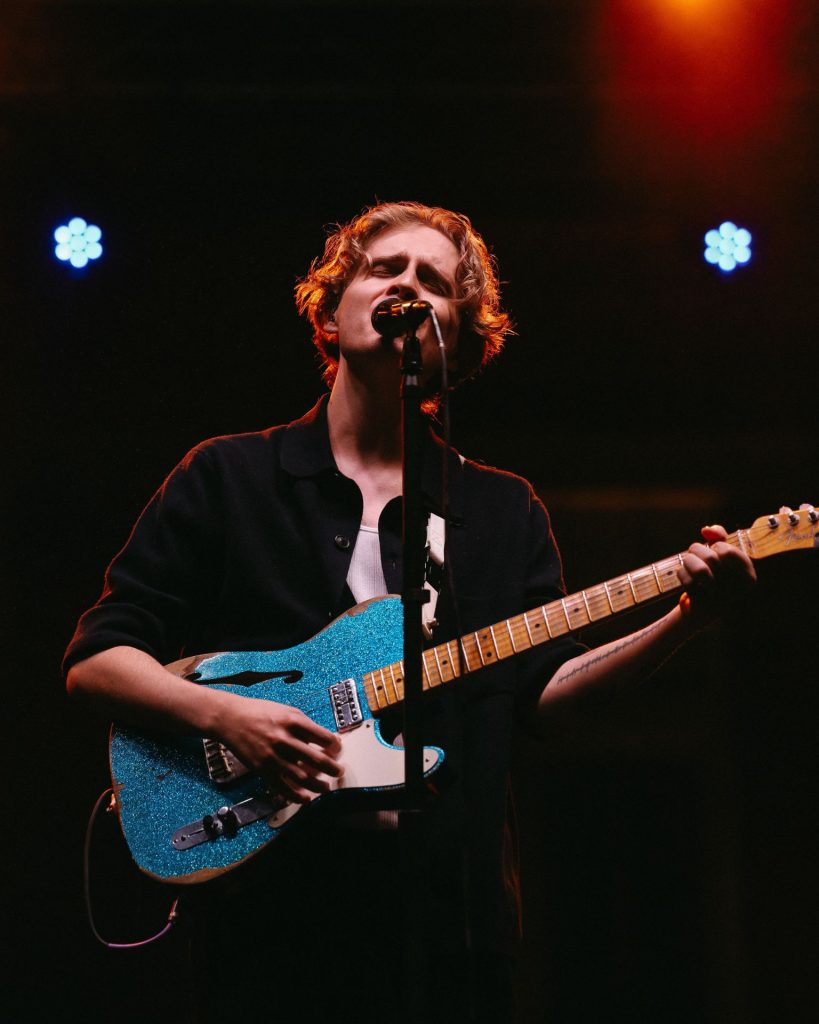 a performer singing with electric guitar