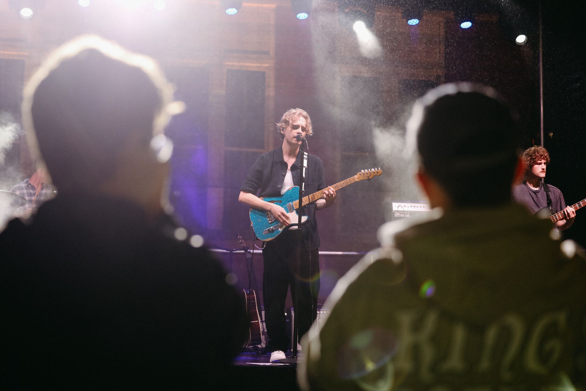 students watching a performer on stage with a guitar