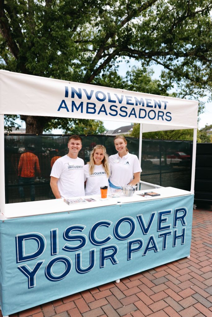 Involvement Ambassadors standing at a booth on the concourse