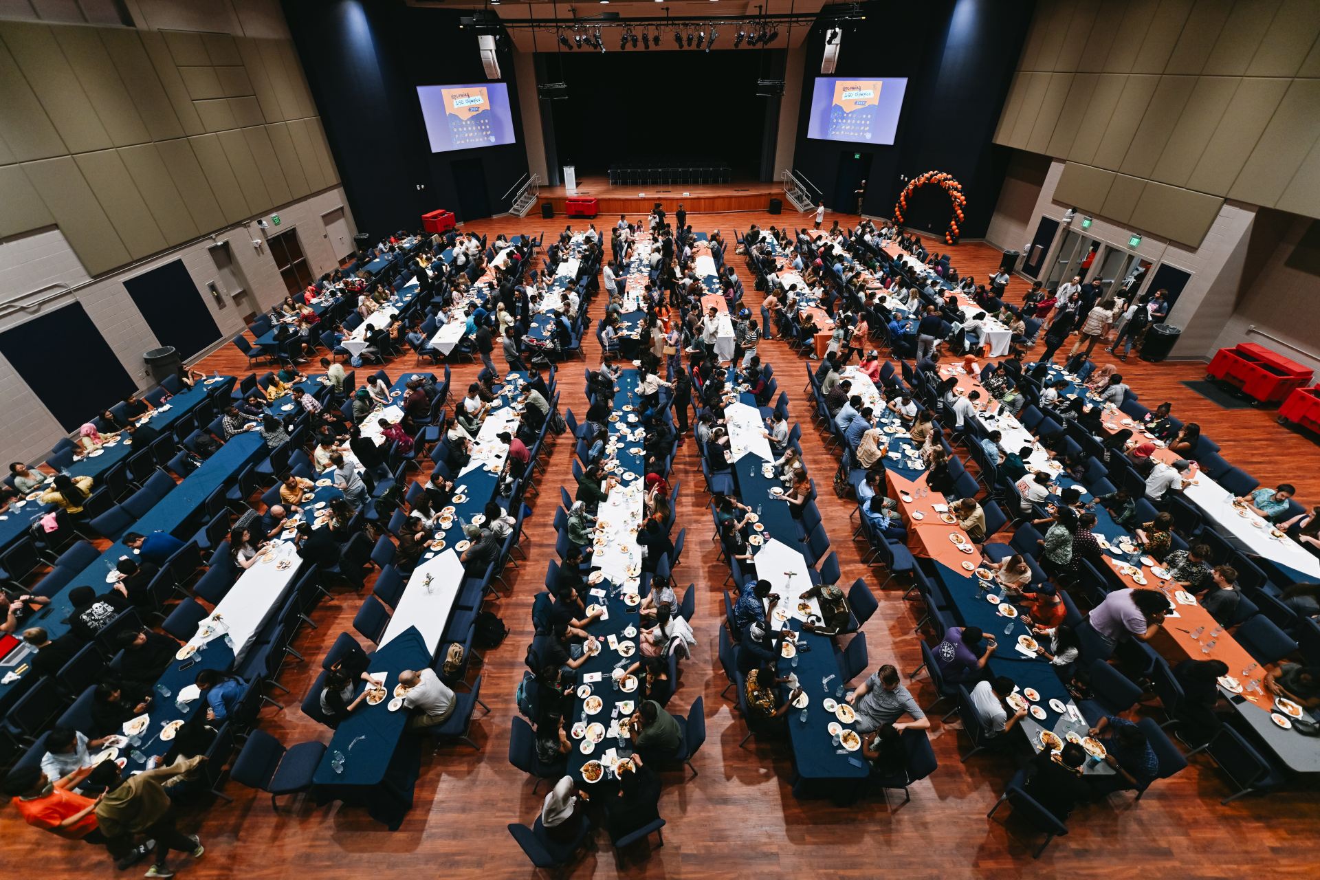 overhead view of a large room filled with people dining at long rectangular tables