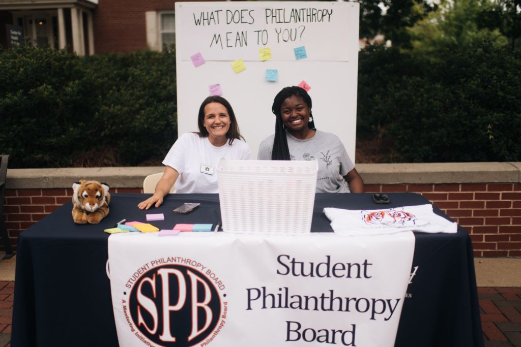 two students from the philanthropy board sit at a table on the Haley concourse