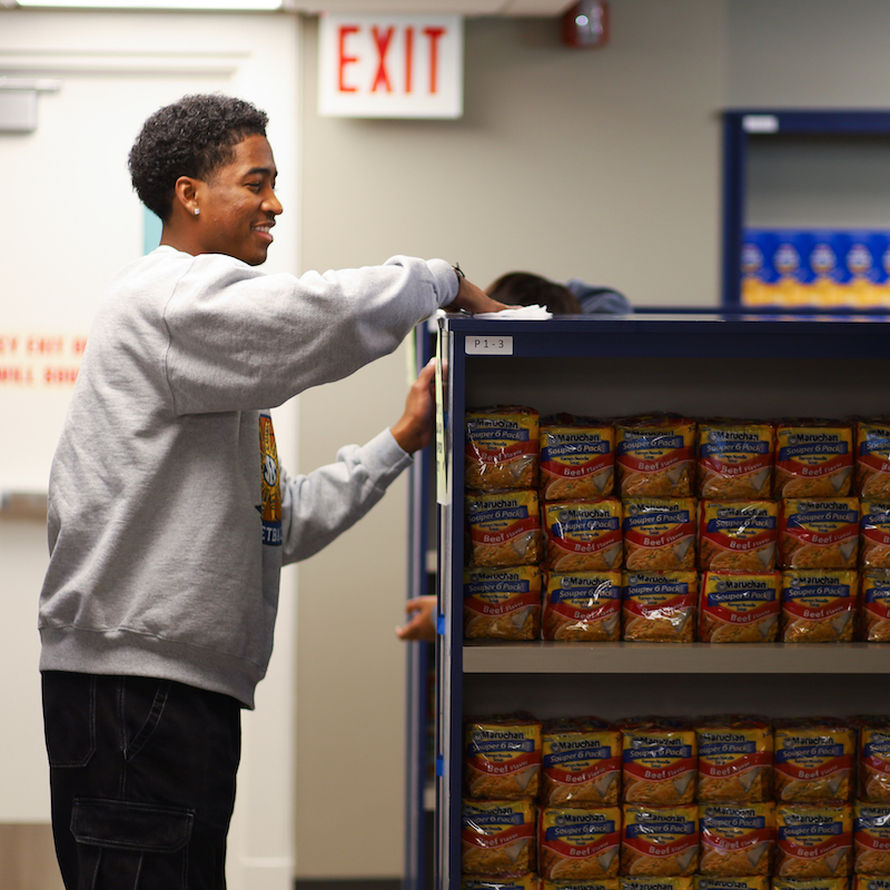 a student standing near a shelf filled with packs of ramen