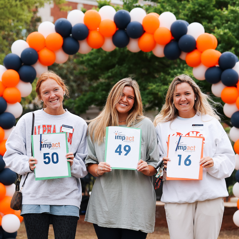 three students posing with numbered signs