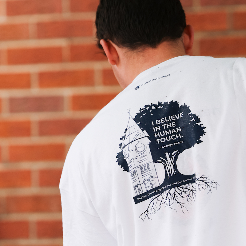 Logo with I believe in the human touch on the back of a student's shirt