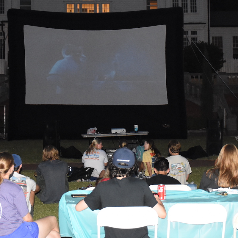 Students watching a movie outside on a blow up screen