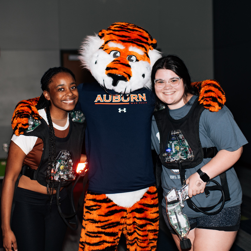 Two students posing with Aubie at a laster tag event
