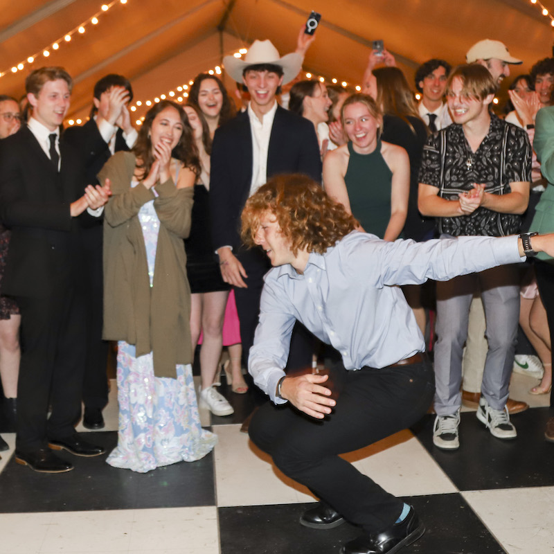 A group of students cheers on another student on the dance floor