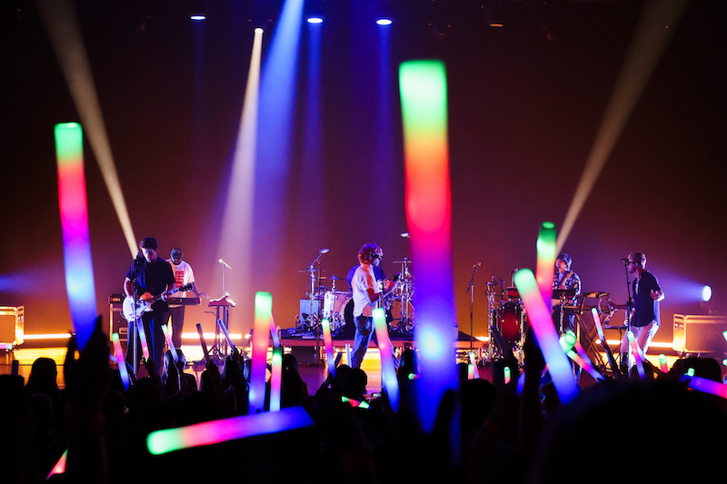 a band playing on a stage surrounded by multicolored lights