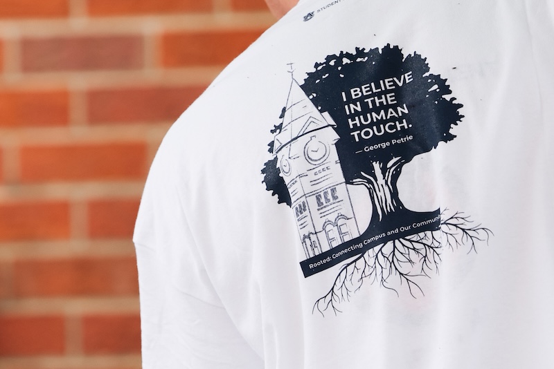 Logo with I believe in the human touch on the back of a student's shirt