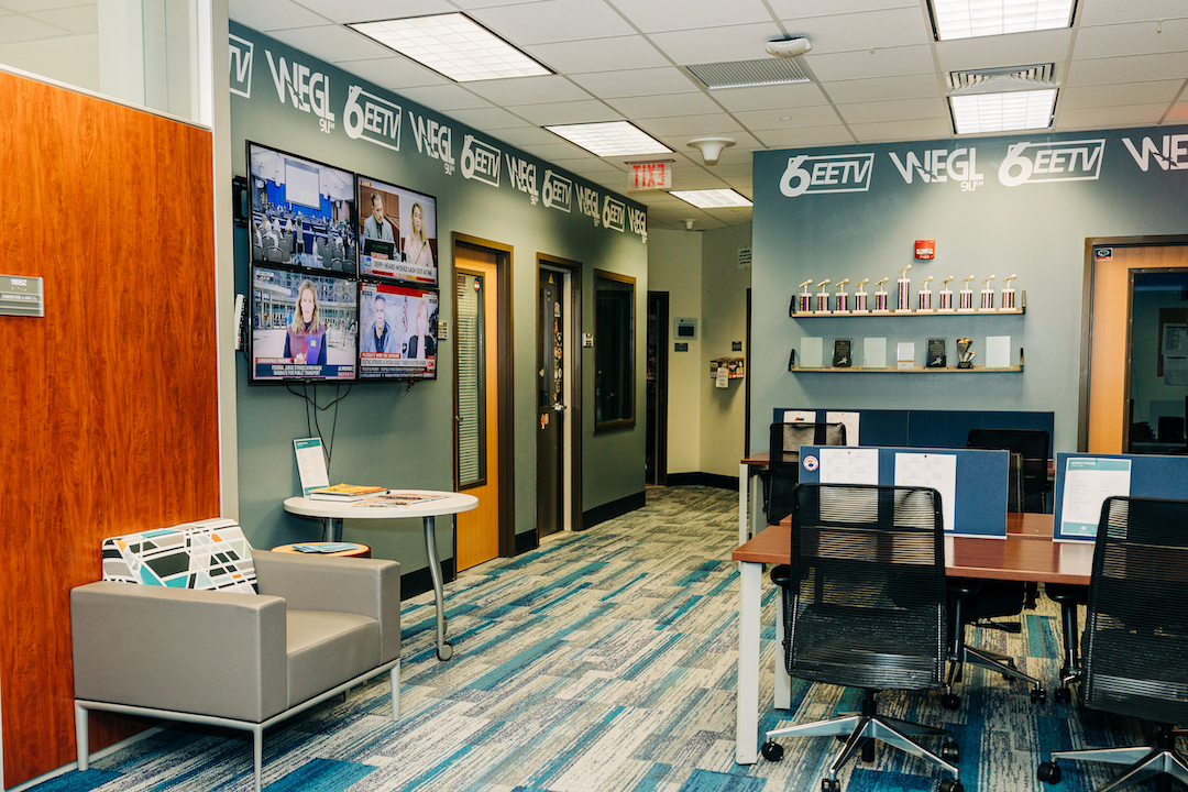 The Student Media Suite in MSC 1105 showing student workspaces, tvs on the wall, a shelf of awards and office spaces.