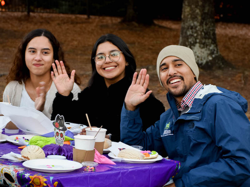 Three students sitting at a table posing for a photo